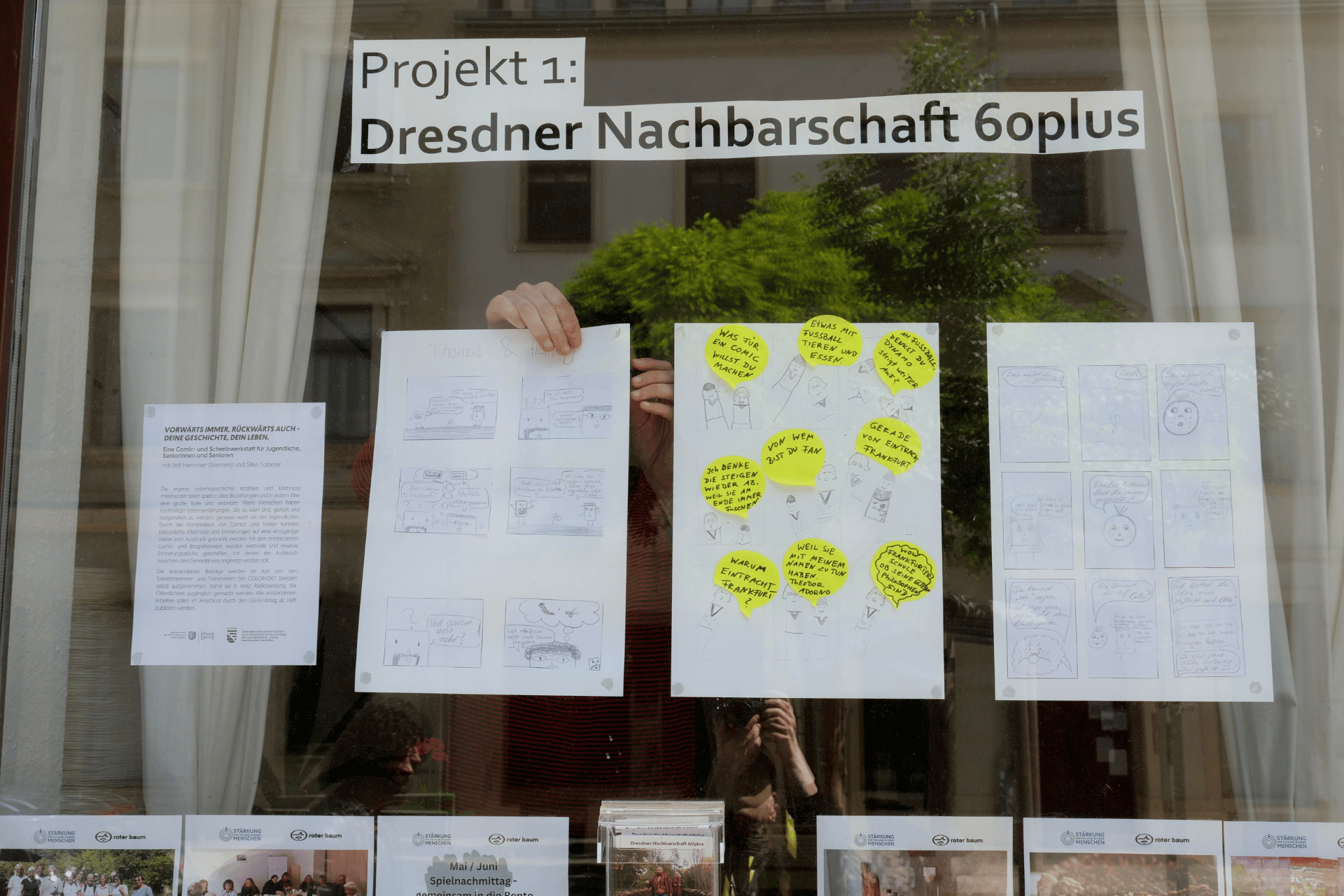 Aushang zum Projekt Dresdner Nachbarschaft 60plus mit gezeichneten Comics an einem Fenster.